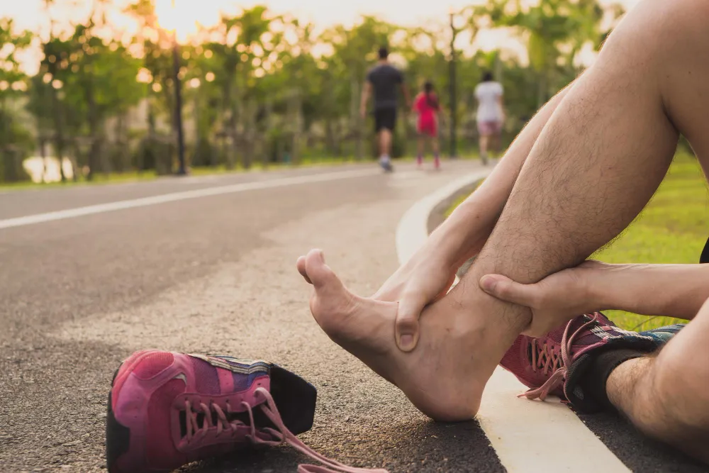 Runner holding his foot in pain, showing posterior tibial tendon strain after high-impact exercise